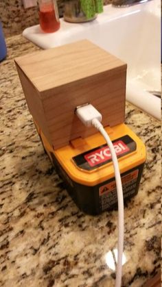 an electronic device is plugged in to a wooden box on the counter next to a sink