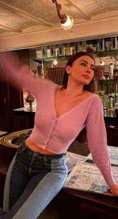 a woman in jeans leaning on a bar counter