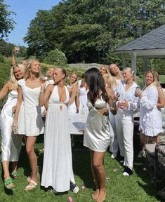 a group of women standing next to each other on top of a lush green field