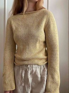 a woman standing in front of a door wearing a yellow sweater