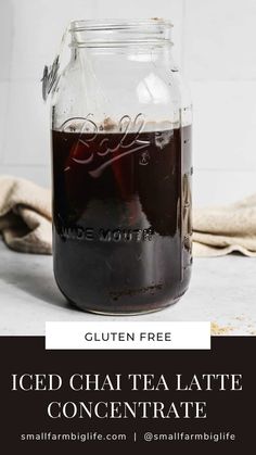 a glass jar filled with iced chai tea latte concentrate on top of a table