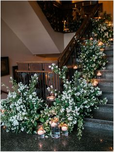 candles are lit on the stairs near flowers and greenery