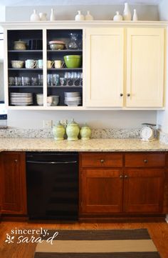 a kitchen with white cabinets and black dishwasher