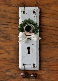 an old key board with a wreath on it and some bells hanging from the side