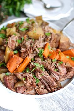 a white bowl filled with meat, potatoes and carrots