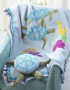 a crocheted turtle is sitting on a chair with a blanket draped over it