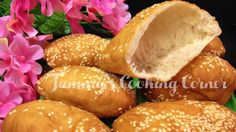 buns with sesame seeds are piled on top of each other in front of pink flowers