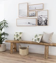 a wooden bench sitting in front of a wall with pictures on the wall above it