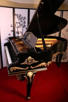 a grand piano sitting on top of a red carpet