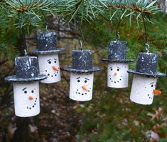 four snowman ornaments hanging from a pine tree