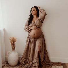 a pregnant woman leaning against a wall with her hands on her head and arms behind her back