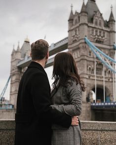 a man and woman standing next to each other in front of the tower bridge, london