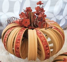 a decorative pumpkin made out of strips of tape with flowers in the center and leaves on top