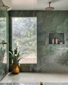 a bathroom with green marble walls and flooring next to a large glass shower door