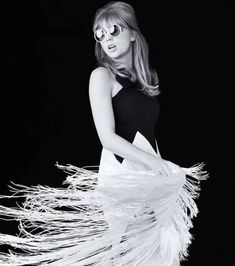 a woman in black and white is holding a feathered dress with sunglasses on her face