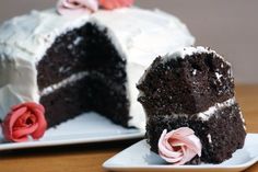 two slices of chocolate cake with white frosting and pink flowers on each slice, sitting on plates