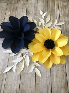 two paper flowers sitting on top of a wooden table