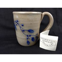 a ceramic mug with blue flowers on it next to a tag that says salmonon falls stoneware