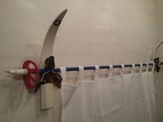 a pair of scissors hanging on the side of a shower curtain rod with hooks attached to it