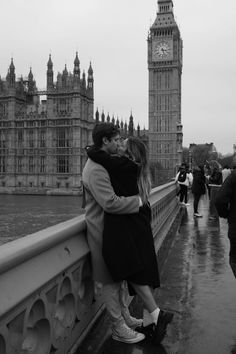 a man and woman kissing on a bridge with big ben in the background