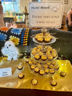 a table topped with lots of cupcakes on top of a yellow cloth covered table