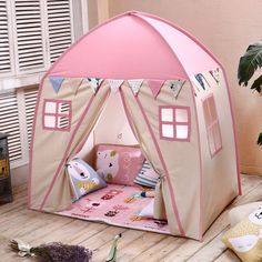 a child's play tent on the floor next to a potted plant and window