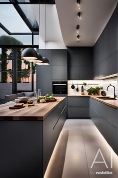 a modern kitchen with grey cabinets and wooden counter tops is lit by pendant lights that hang from the ceiling