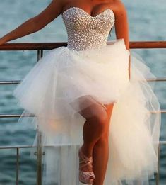 a woman in a short white dress leaning on a railing