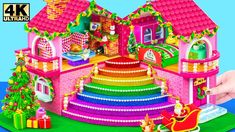 a pink doll house with christmas decorations on the top and stairs leading up to it