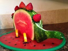 a watermelon shaped like a dinosaur with strawberries on it's head