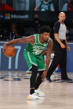 a basketball player dribbling the ball during a game with other players in the background