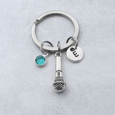 a silver keychain with a blue stone and the letter e on it's side