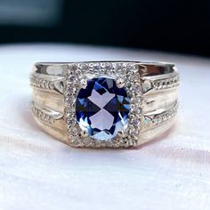 a blue and white diamond ring sitting on top of a table next to another ring