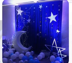 a room with balloons, stars and moon decorations on the wall in front of a blue curtain