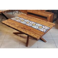 a wooden table sitting on top of a tiled floor next to two benches and tables