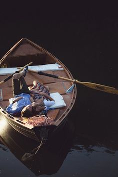 two people are sitting in a small boat on the water with oars and paddles