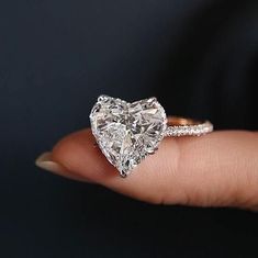 a woman's hand holding a heart shaped diamond ring