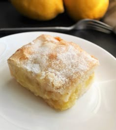 a piece of cake sitting on top of a white plate next to two lemons