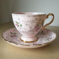 a cup and saucer sitting on top of a wooden table next to a wall