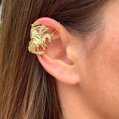 a close up of a person's ear wearing a pair of gold colored earrings