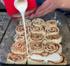 cinnamon rolls being poured onto a baking pan