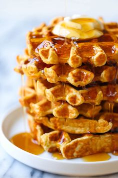 a stack of waffles covered in syrup and butter