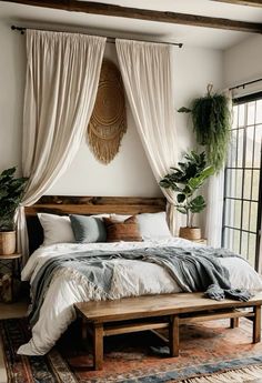 a large bed sitting in a bedroom next to a wooden table and plant on top of it