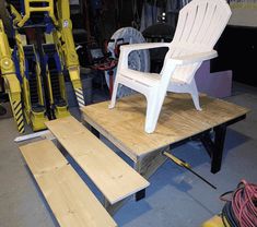 a white plastic chair sitting on top of a wooden platform in a garage next to other tools