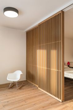 a bedroom with wooden slats on the wall and a white chair next to it