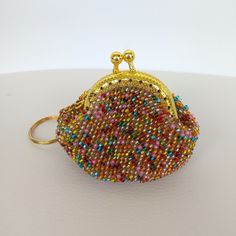 a small purse with beads on it sitting on top of a white table next to a keychain