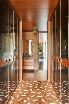 the hallway is lined with mirrored doors and wooden cabinets, along with an area rug on the floor