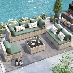 an outdoor living area with couches, tables and chairs next to the water's edge