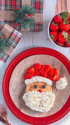 a plate topped with strawberries and whipped cream next to a bowl of strawberries