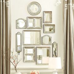 a living room filled with white furniture and mirrors on the wall above it's fireplace